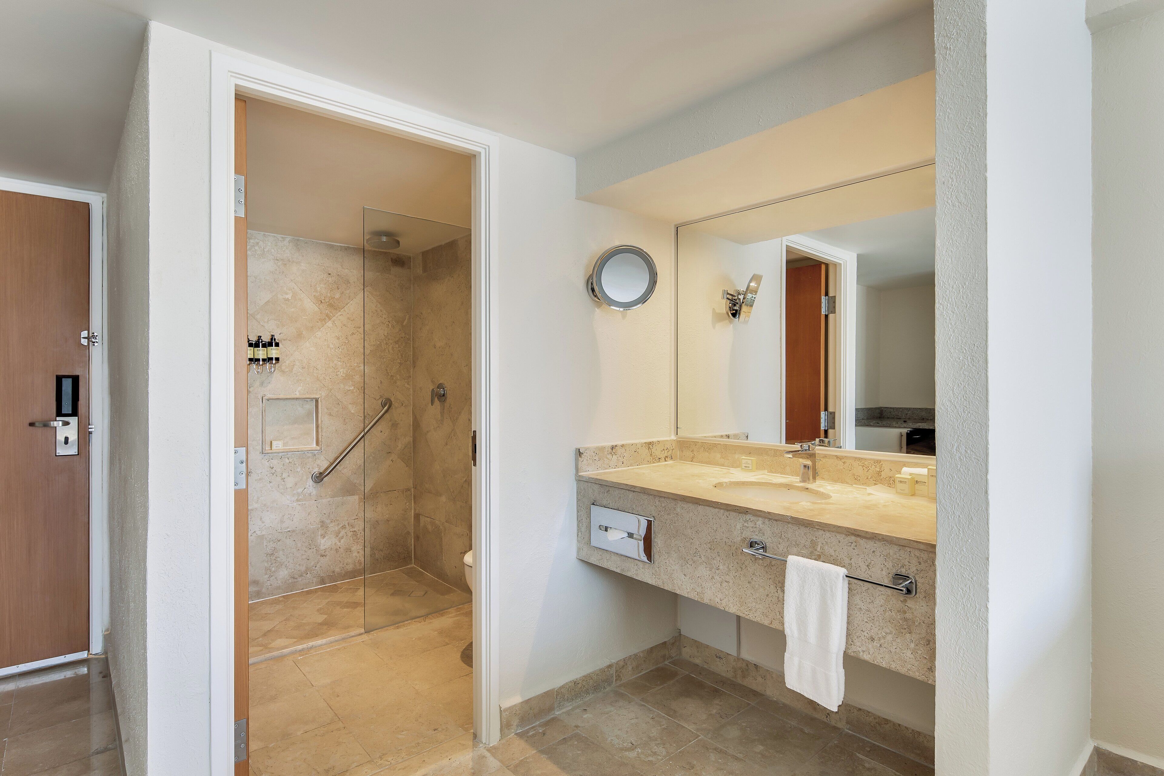 A modern bathroom with a shower, a sink with a towel, and a mirror.