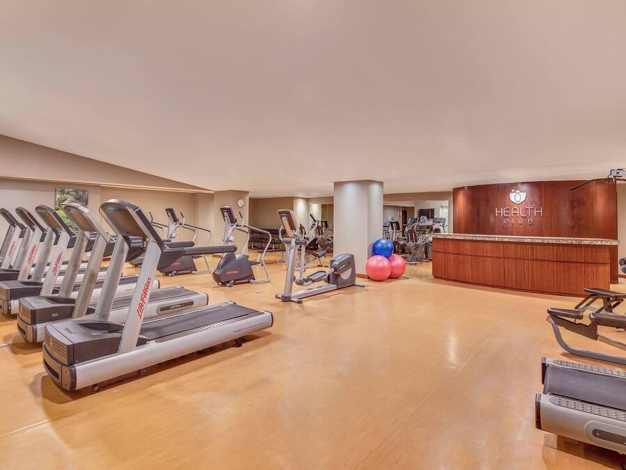 Ein Fitnessstudio mit mehreren Laufbändern, Crosstrainern und weiteren Trainingsgeräten.