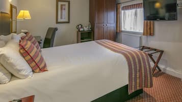 Una habitación de hotel con una cama grande, un escritorio con lámpara, un televisor y un armario.