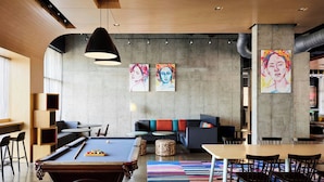Un espace de détente moderne avec une table de billard, des sièges et des œuvres d’art accrochées aux murs.
