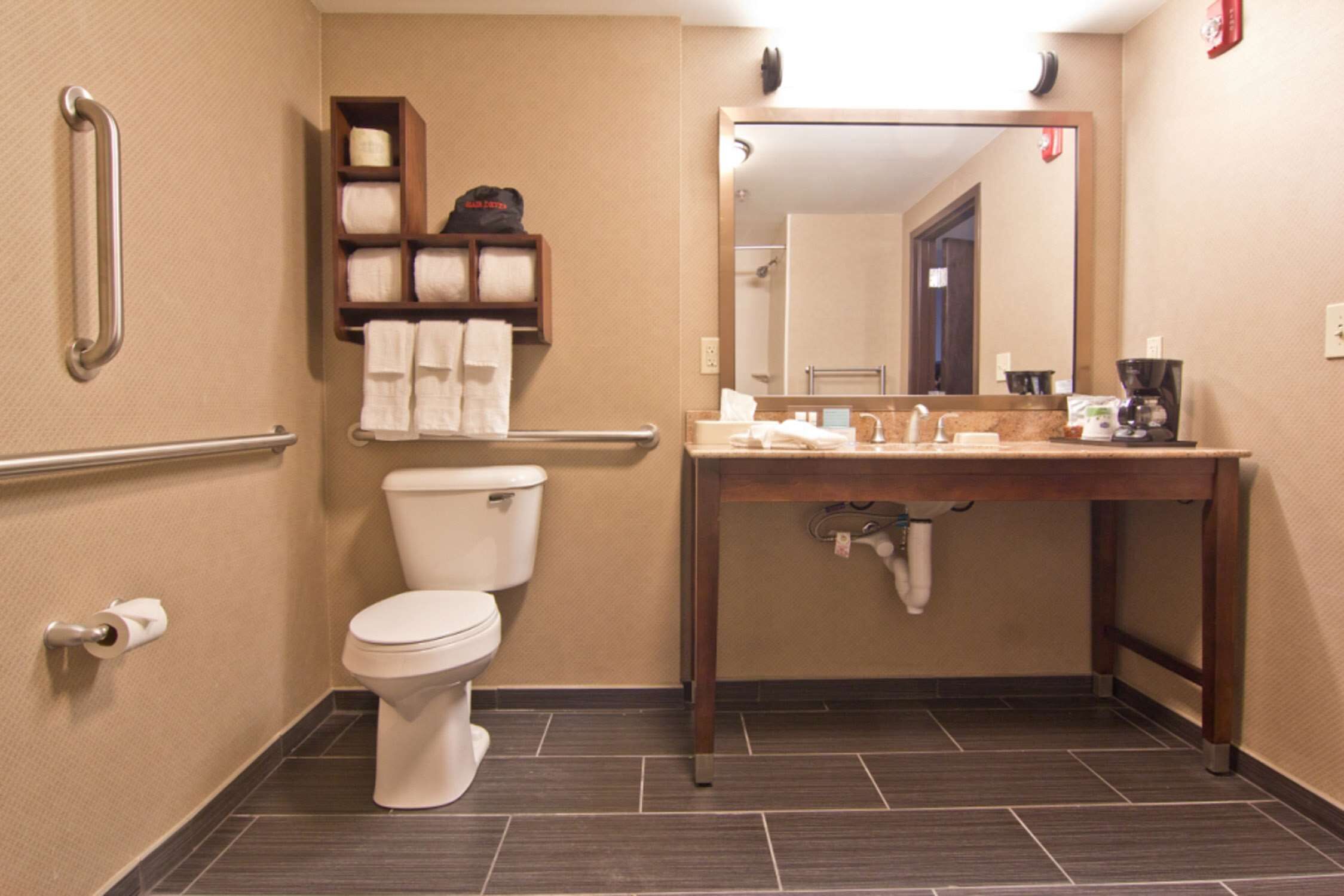 Une salle de bain équipée de toilettes, d’un lavabo, d’un miroir et d’un porte-serviettes.