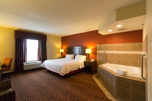 A hotel room with a bed, two bedside lamps, a desk, an air conditioner, a window with curtains, and a bathroom with a bathtub and towel rack. - Hampton Inn Columbus-South (Grove City)