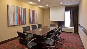 A conference room with a long table, six chairs, two large abstract paintings, a projector screen, and an air conditioning unit. - Hampton Inn Columbus-South (Grove City)