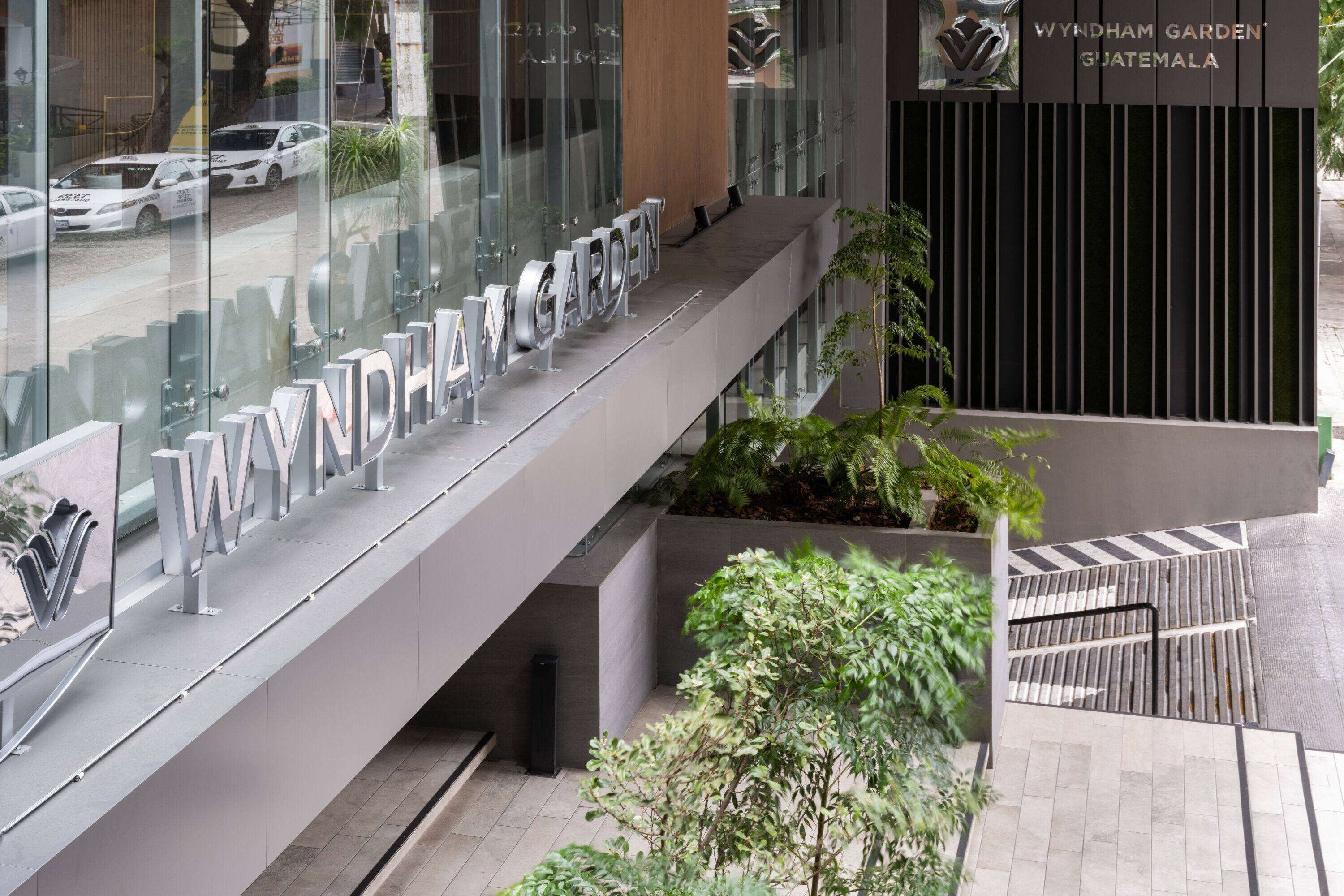 Un bâtiment moderne avec une façade en verre et une enseigne indiquant « WYNDHAM GARDEN GUATEMALA ».