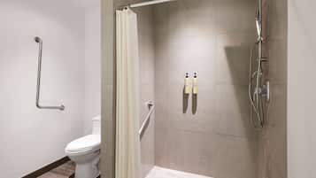 Un baño moderno con ducha, inodoro y barras de apoyo.