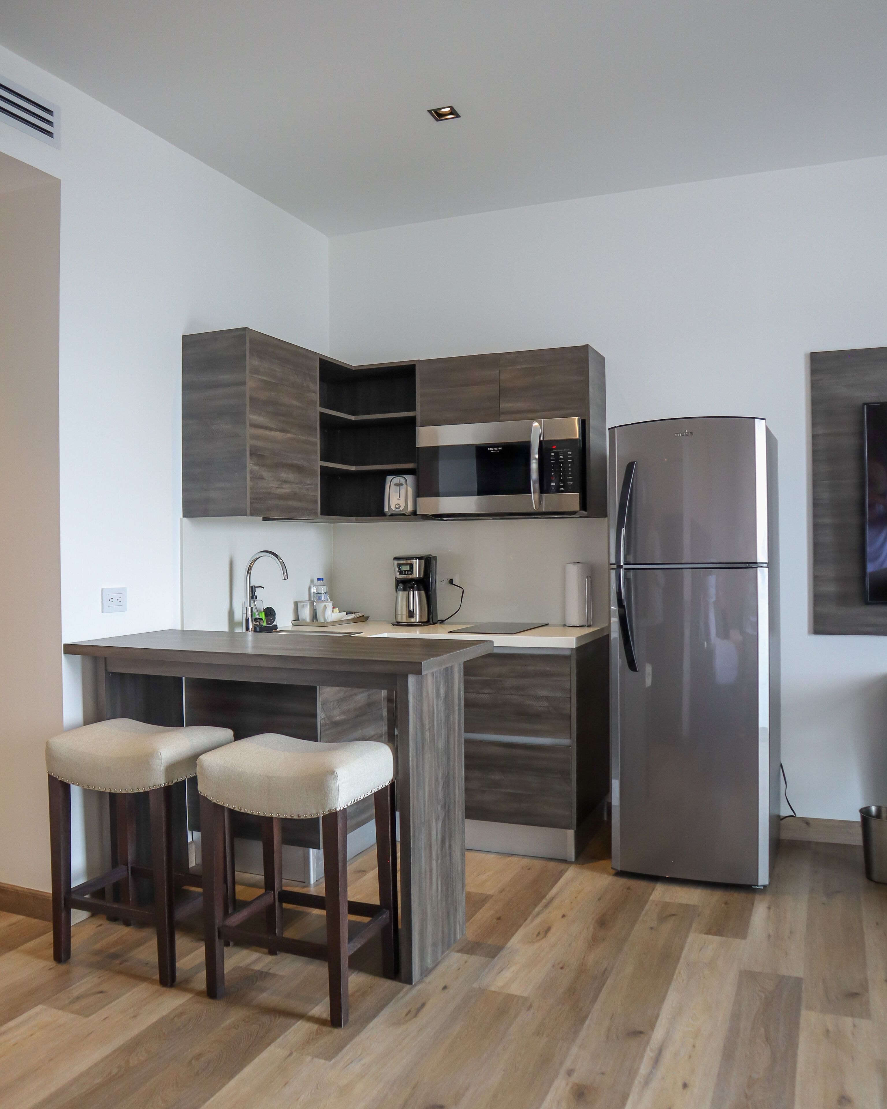 A modern kitchen with a built-in microwave, refrigerator, and a coffee maker on the counter.