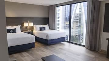 A hotel room with two beds, a nightstand, a lamp, a desk, and a large window with curtains.