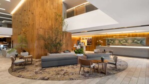 A modern lobby with a wooden accent wall, seating areas, and a reception desk.