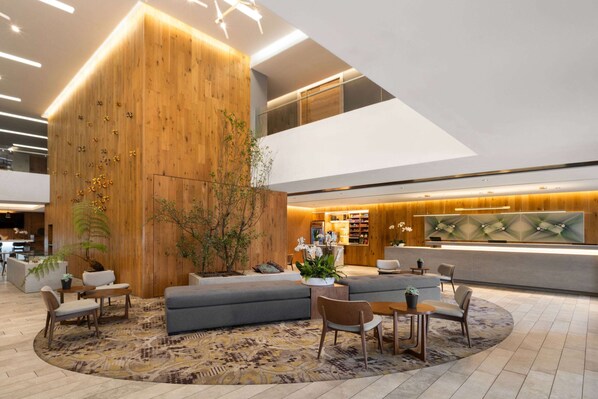 A modern lobby with a wooden accent wall, seating areas, and a reception desk.