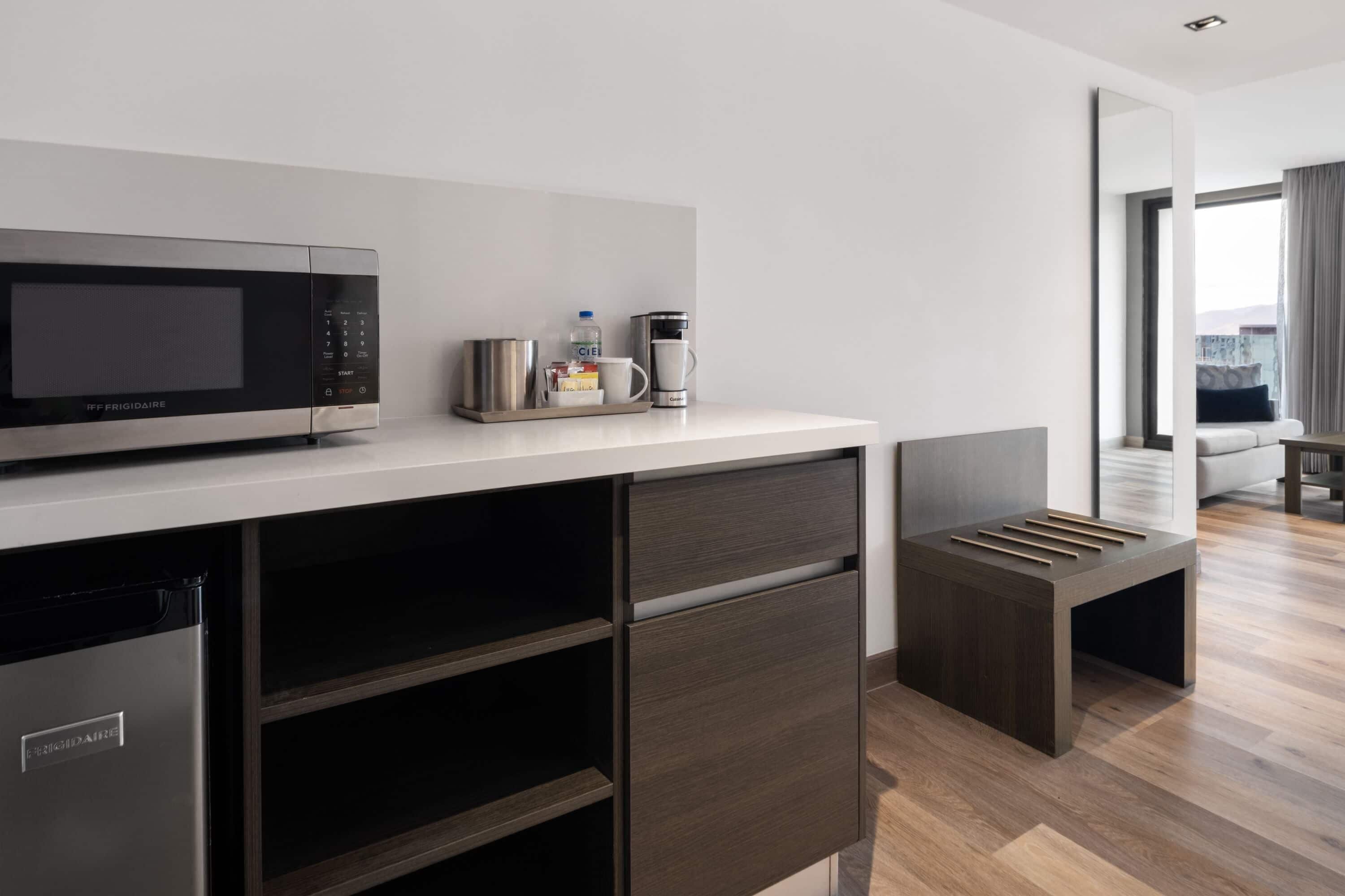 A modern kitchen with a built-in microwave, coffee maker, and storage cabinets.