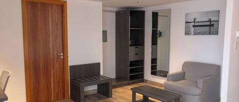 Una sala de estar moderna con una puerta de madera, un sofá gris, un banco oscuro y una mesita.