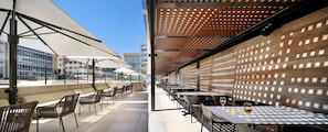 Une terrasse extérieure avec des tables et des chaises, une pergola en bois et une vue sur les bâtiments en arrière-plan.