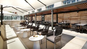 Un espace extérieur aménagé avec des tables et des chaises, une pergola et une vue sur la ville.