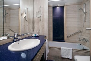 A modern bathroom with a large sink, a mirror, a bathtub, and a shower.