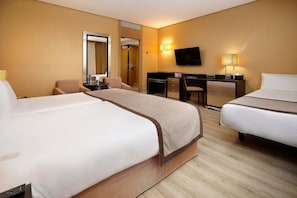 A hotel room with two beds, a desk, a chair, a TV, and a mirror.