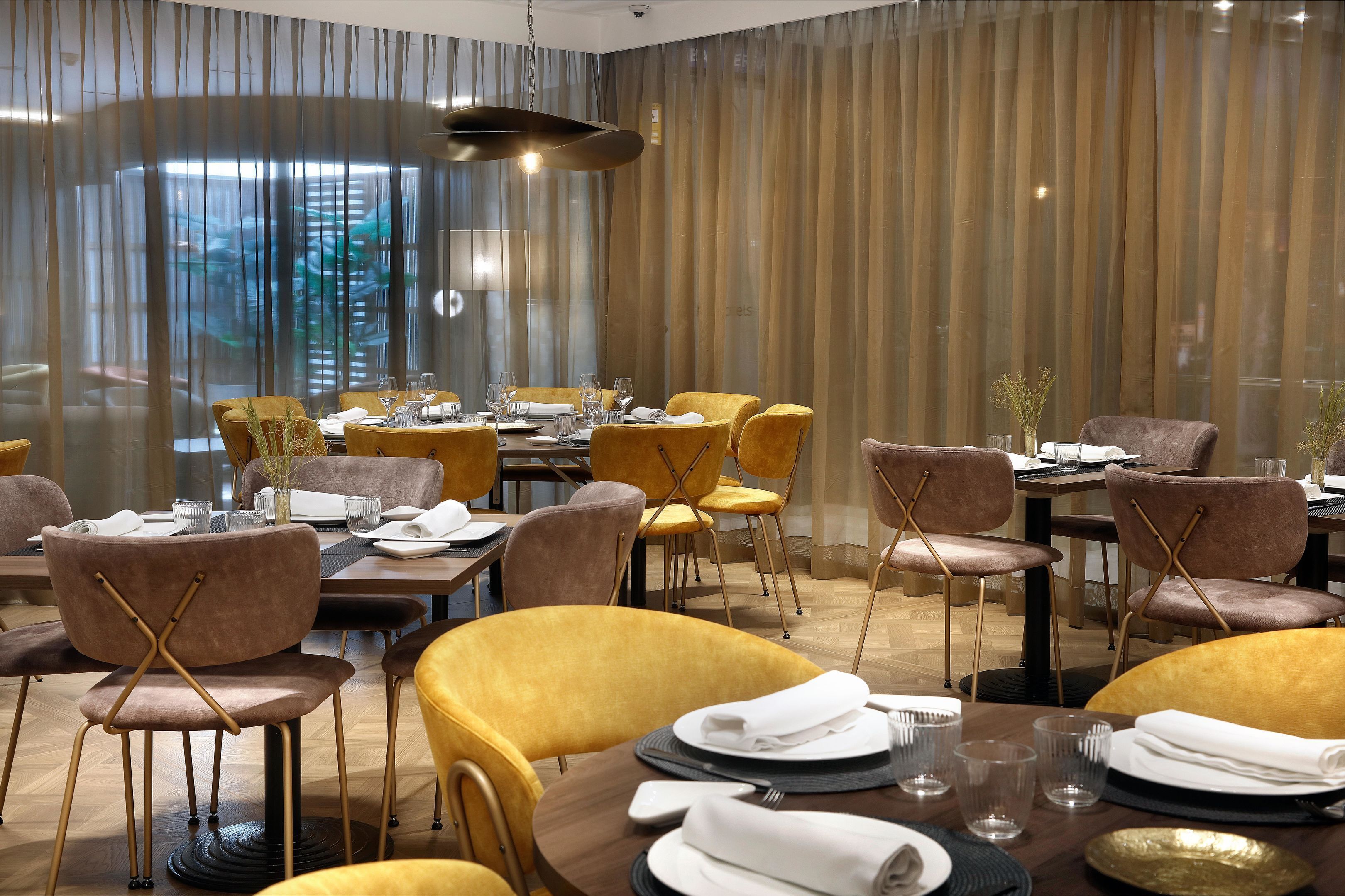Un restaurant avec des tables rondes, des chaises jaunes et un décor intérieur moderne.
