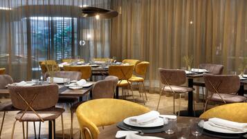 Un restaurant avec des tables rondes, des chaises jaunes et un décor intérieur moderne.