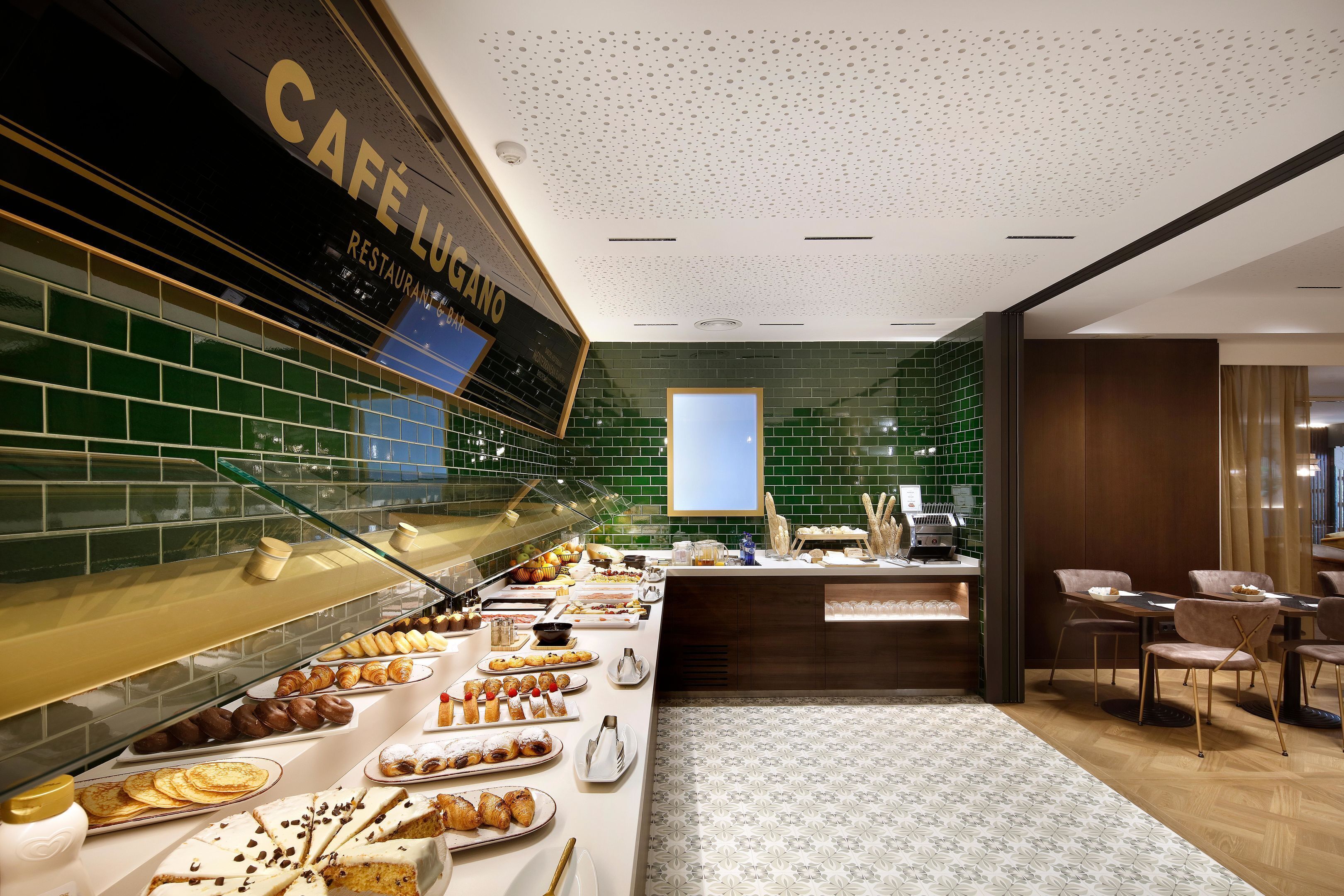 A breakfast buffet area with a variety of pastries and desserts, a coffee station, and a seating area with tables and chairs.