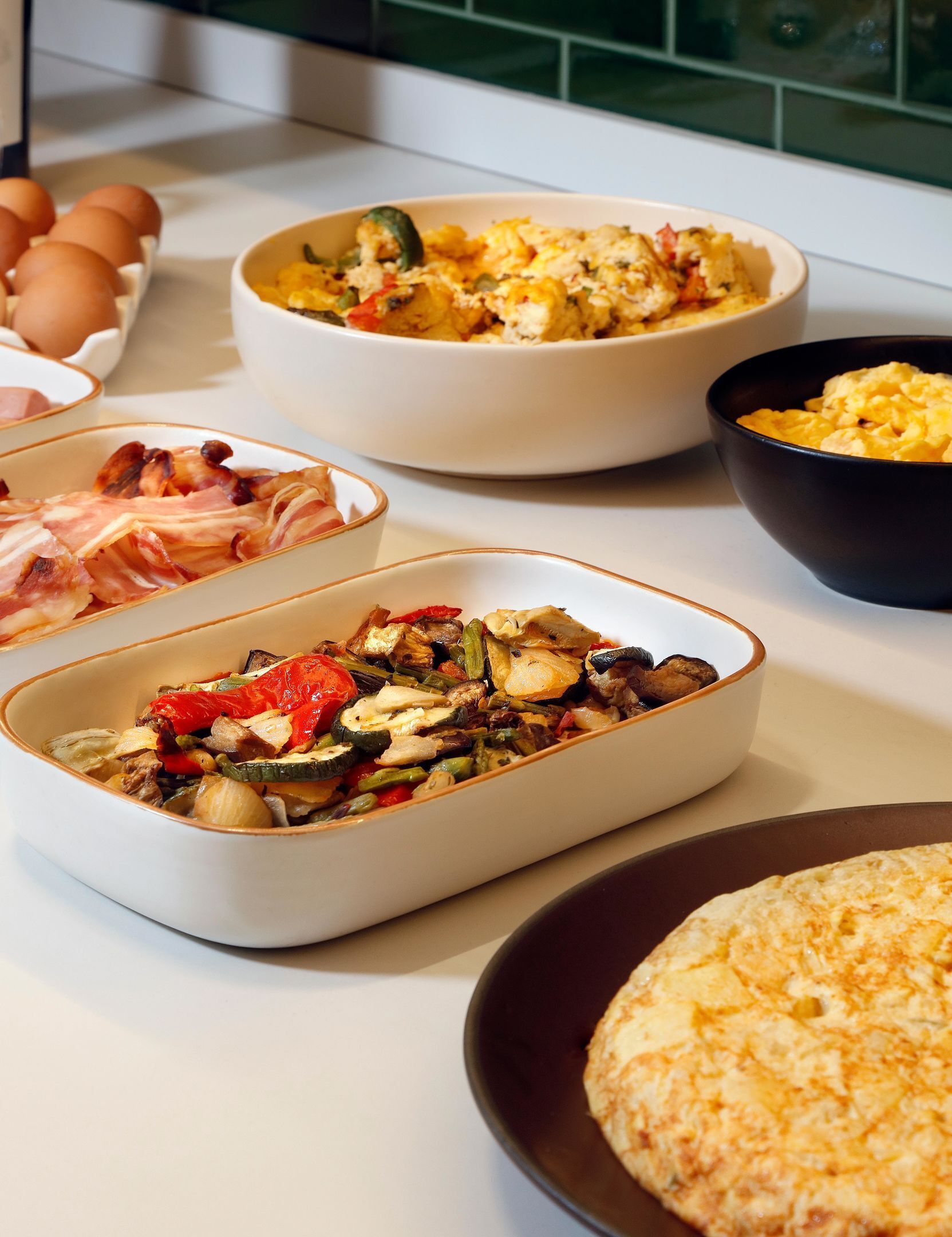 Een ontbijtbuffet met diverse gerechten, waaronder roerei, groenten en vlees.