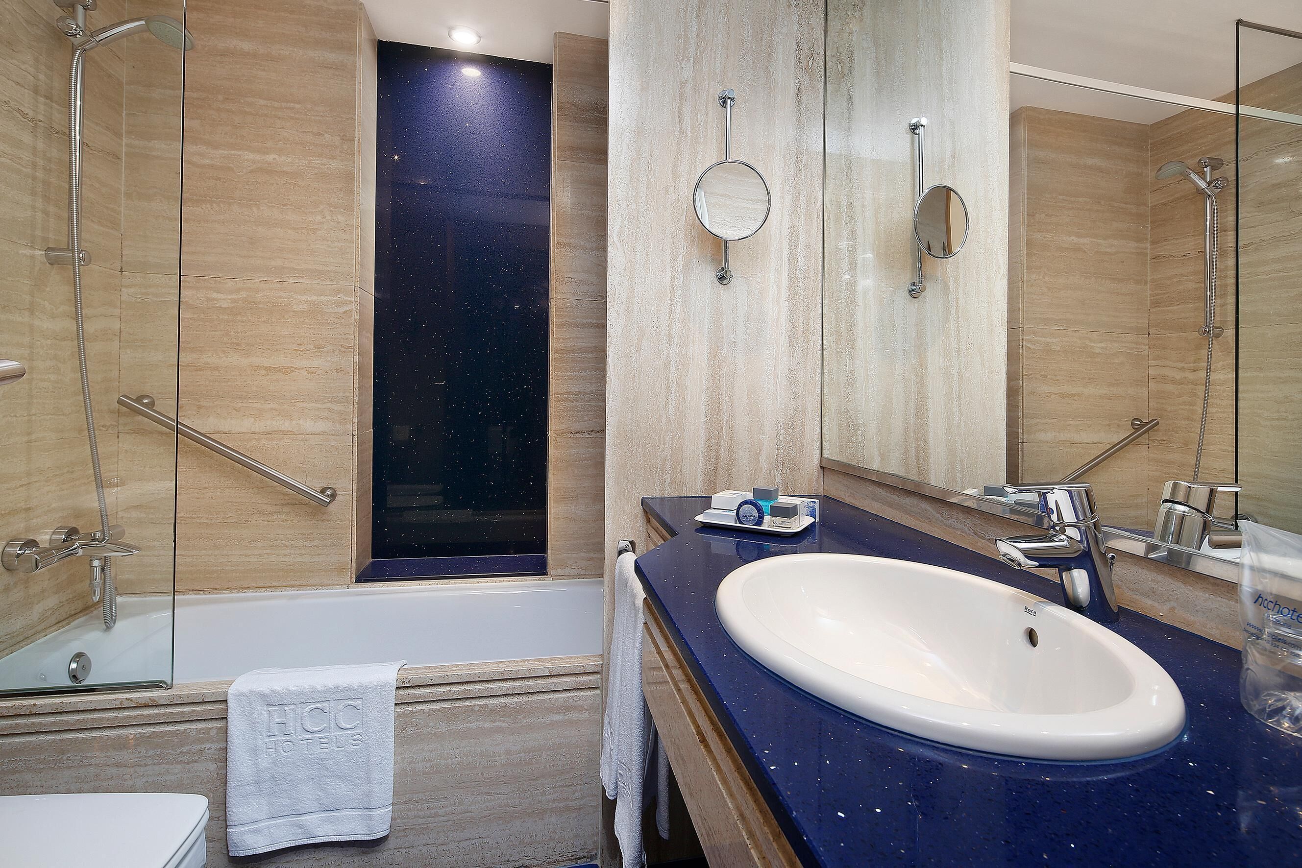 A modern bathroom with a bathtub, a large mirror, and a sink.