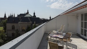 A balcony with a table and chairs, overlooking a historic building with multiple spires and a dome.