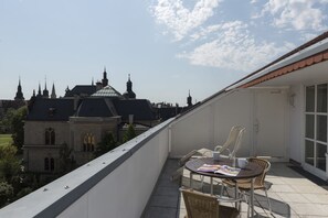 A balcony with a table and chairs, overlooking a historic building with multiple spires and a dome.