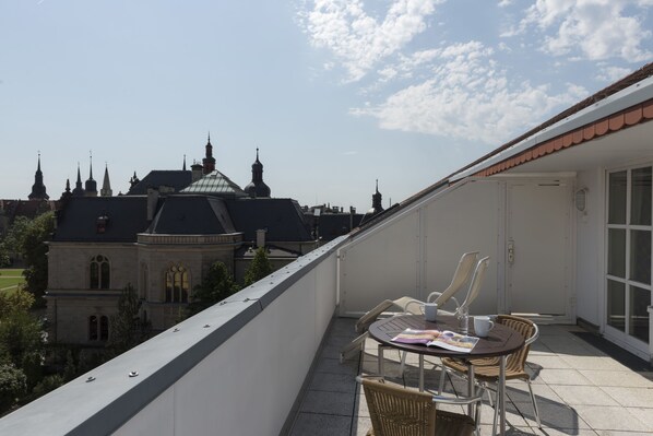 Enjoy breathtaking views of a historic landmark from this balcony with a table and chairs.
