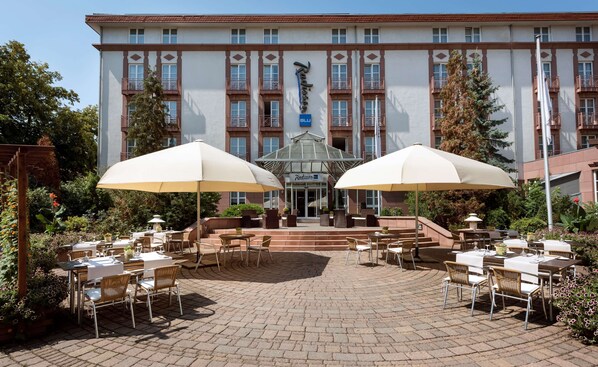 A hotel with outdoor seating, a covered entrance, and a large building facade.