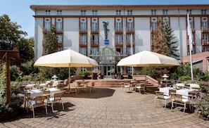 Enter through a glass canopy and into a beautifully landscaped courtyard with outdoor seating areas and brick paving.