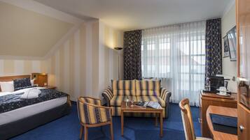 A hotel room with a bed, a sofa, a coffee table, and a desk with a chair.
