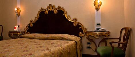 Habitació d'hotel amb un llit gran, una cadira de fusta, dues taules de nit amb làmpades i una làmpada de paret.