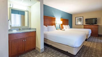 Una habitación de hotel con una cama grande, un aparador de madera, un baño con espejo y una televisión.
