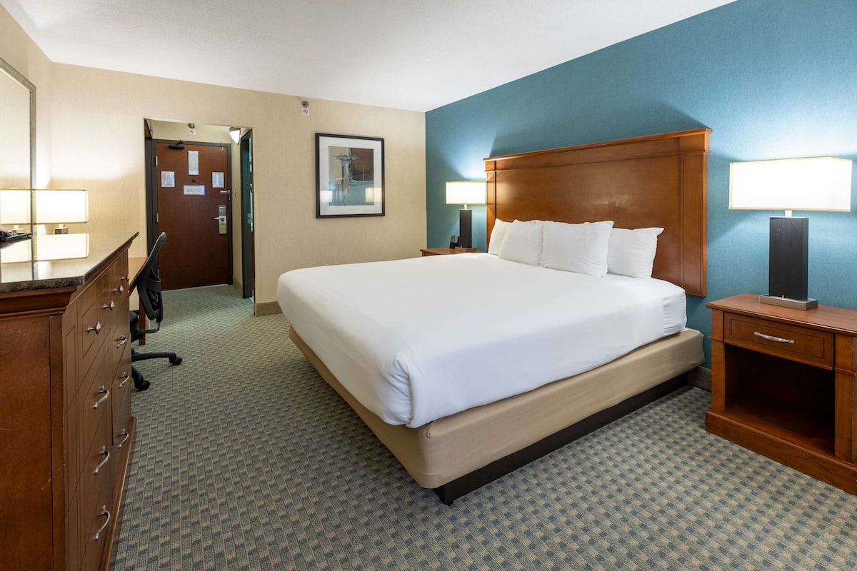 Ein Hotelzimmer mit einem großen Bett, einem Schminktisch, einem Schreibtisch und zwei Lampen.