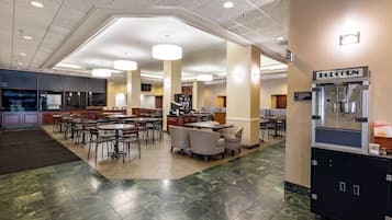 A spacious lobby with multiple seating areas, a popcorn machine, and a self-service beverage station.