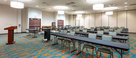 A conference room with multiple tables and chairs, a podium, and a patterned carpet.