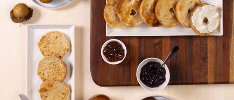 Variedad de opciones para el desayuno, incluyendo muffins, bagels y pan con mermeladas y otros acompañamientos.