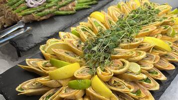 Een buffet met diverse gerechten, waaronder wraps, asperges en ander groenteproduct.