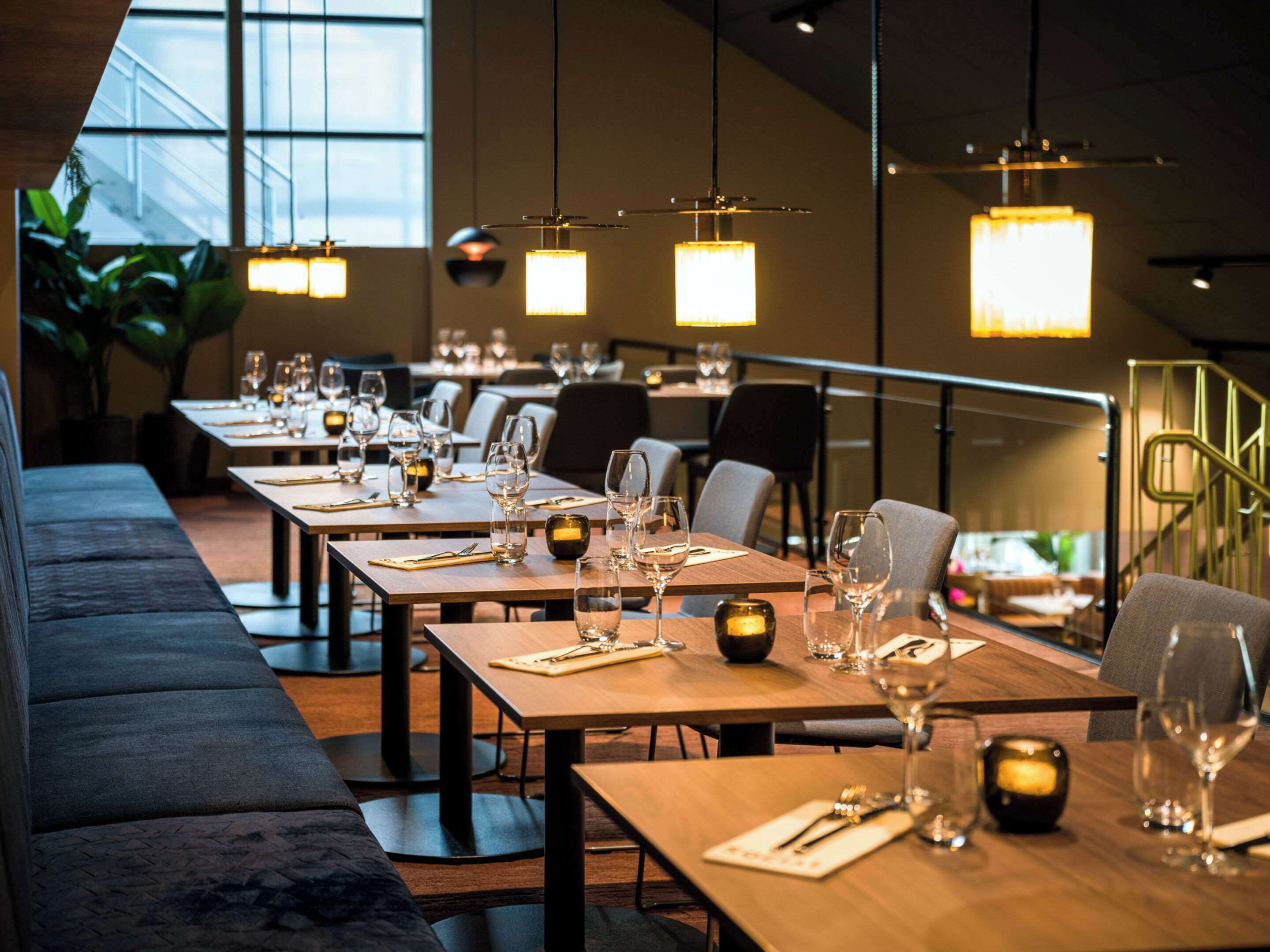 Un restaurante con mesas de madera largas, velas y lámparas colgantes.