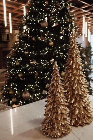 A Christmas tree with lights and ornaments, and two golden pine cone decorations on a table.