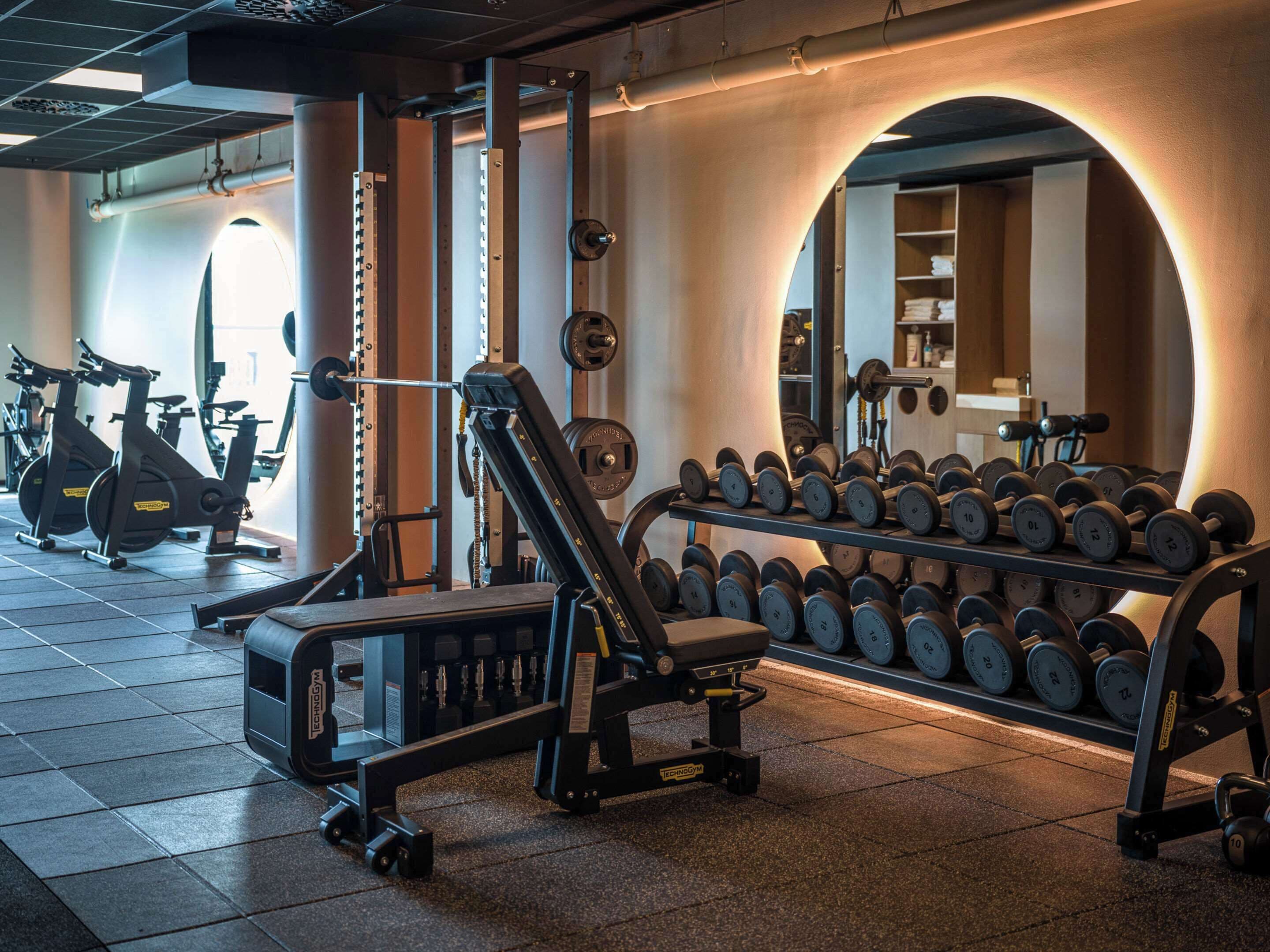 A gym with weightlifting equipment, dumbbells, and exercise machines.
