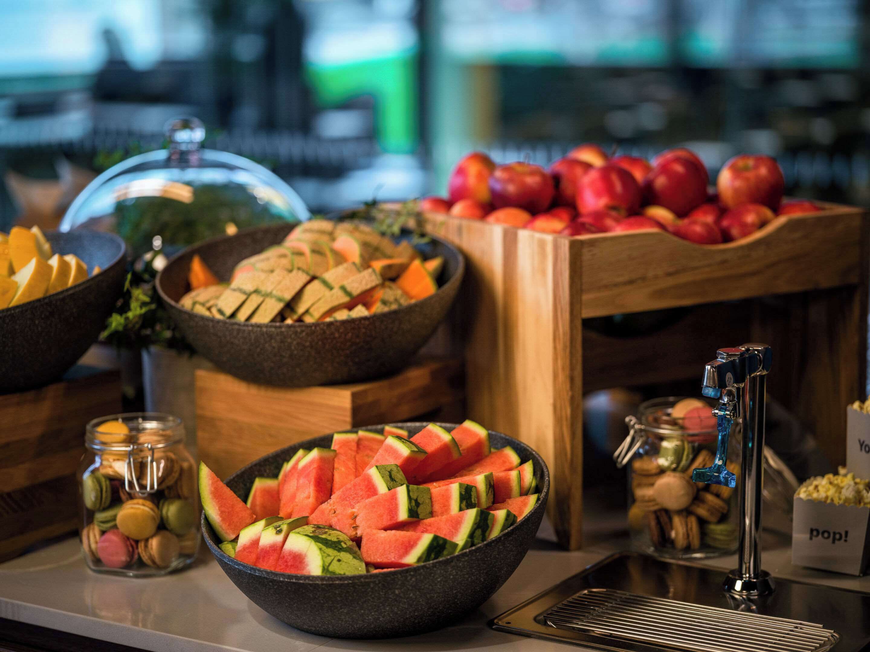 Un bufé con diversos alimentos, como sandía, manzanas y macarons.