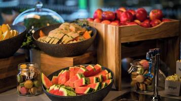 Un bufé con diversos alimentos, como sandía, manzanas y macarons.