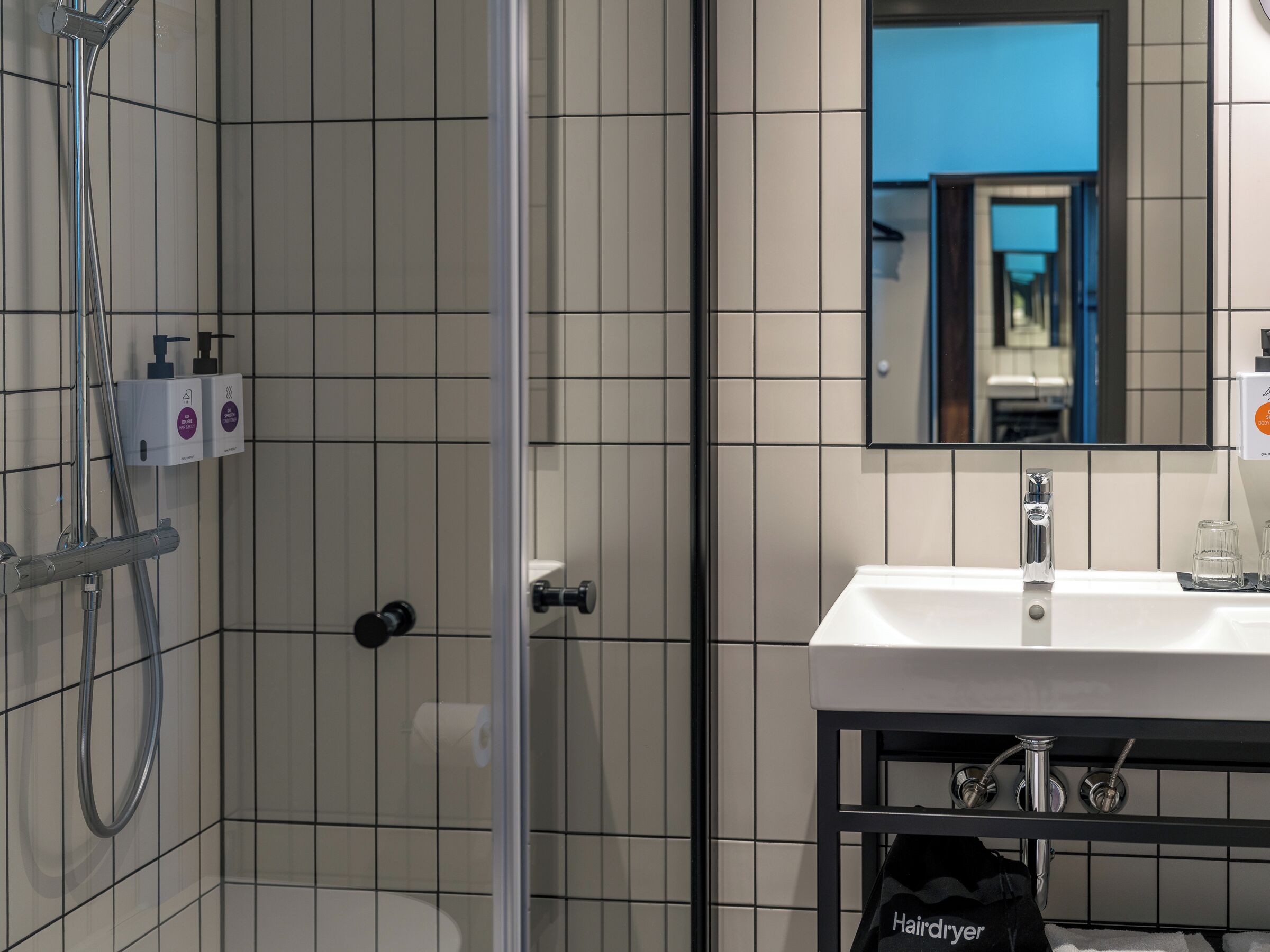 A modern bathroom with a shower, a sink, and a mirror.