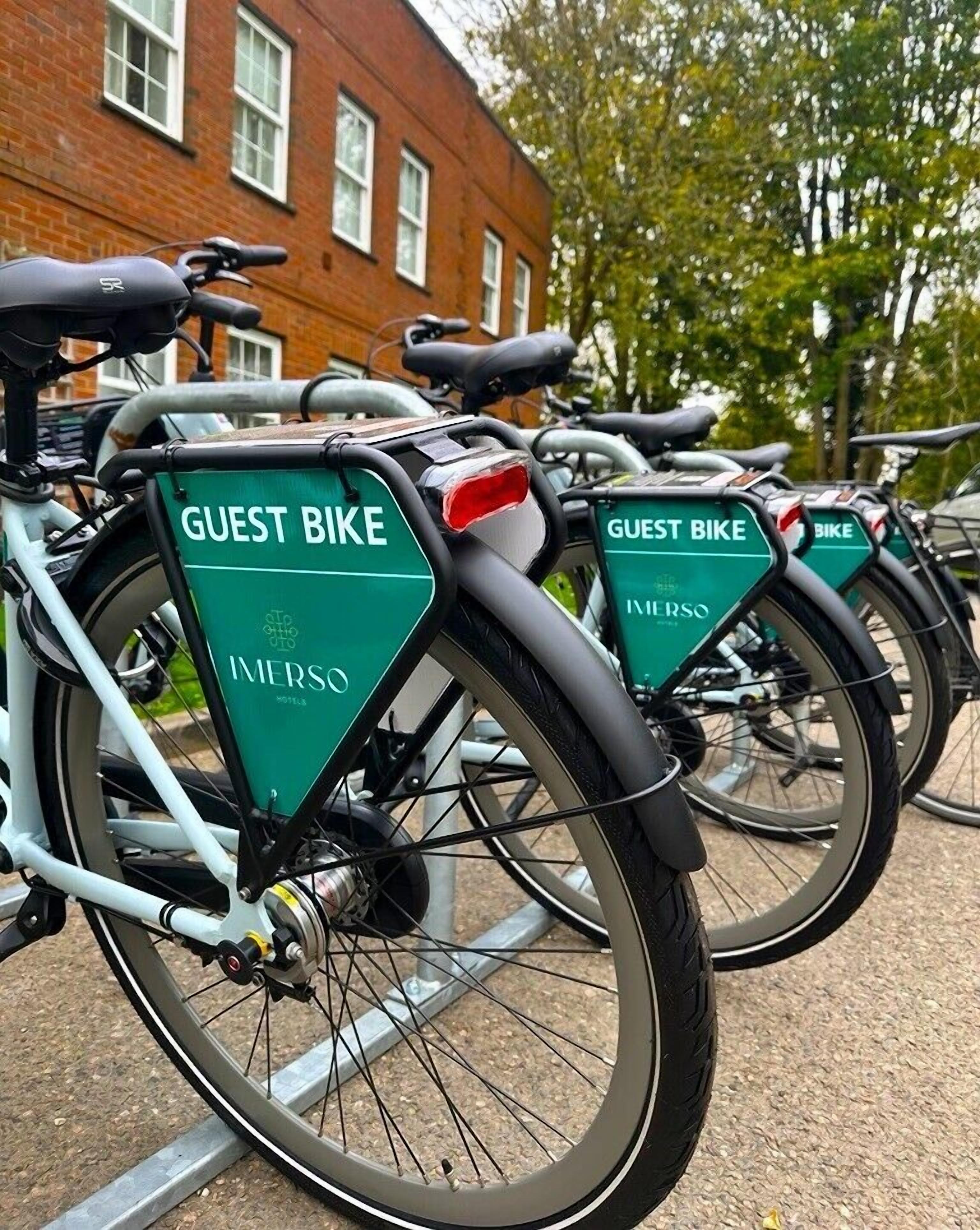 Eine Reihe von Fahrrädern mit dem Aufdruck 'GUEST BIKE' und 'INVERSO'-Branding, ordentlich abgestellt.
