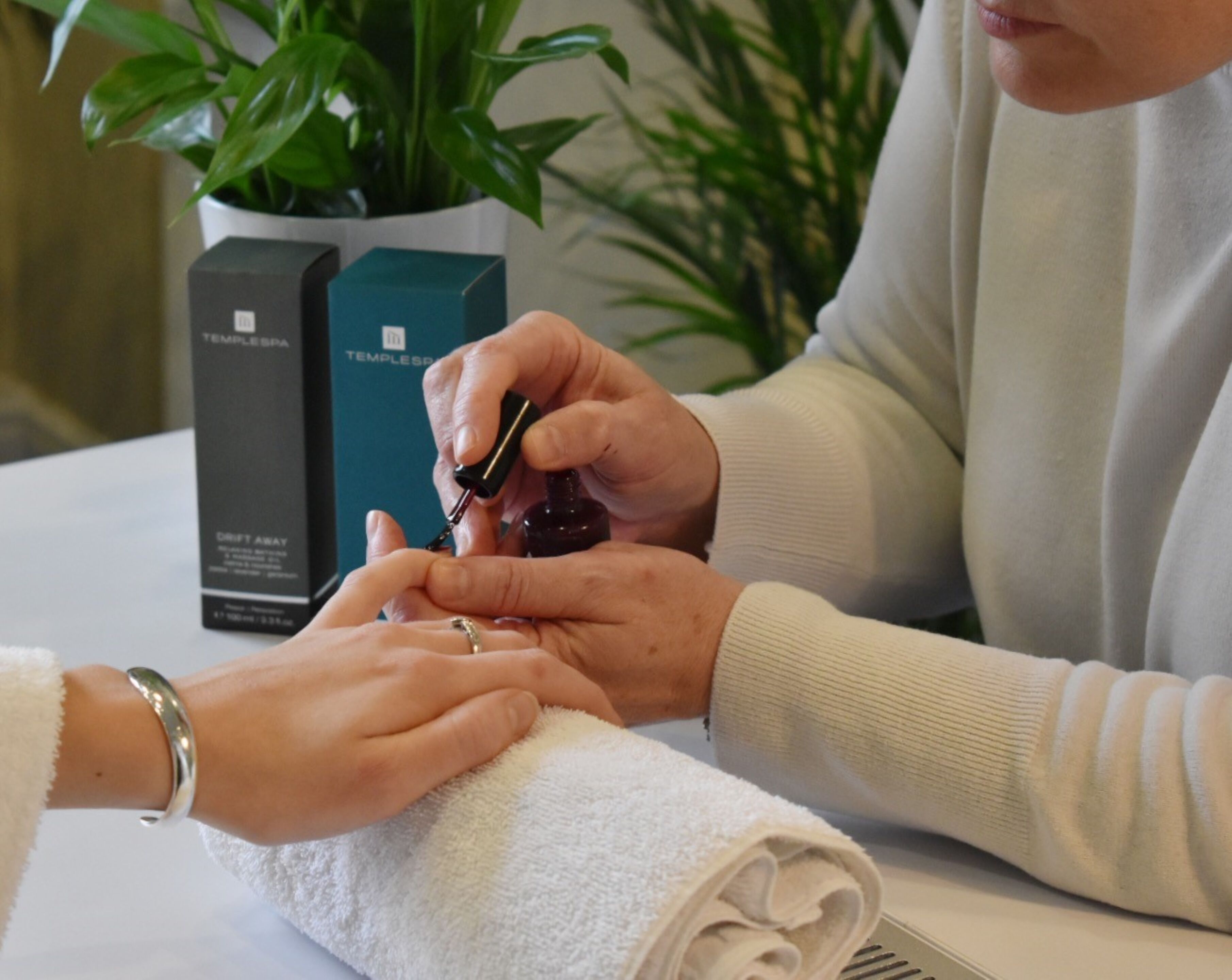 A person applying nail polish to another person's hand.
