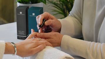 A person applying nail polish to another person's hand.