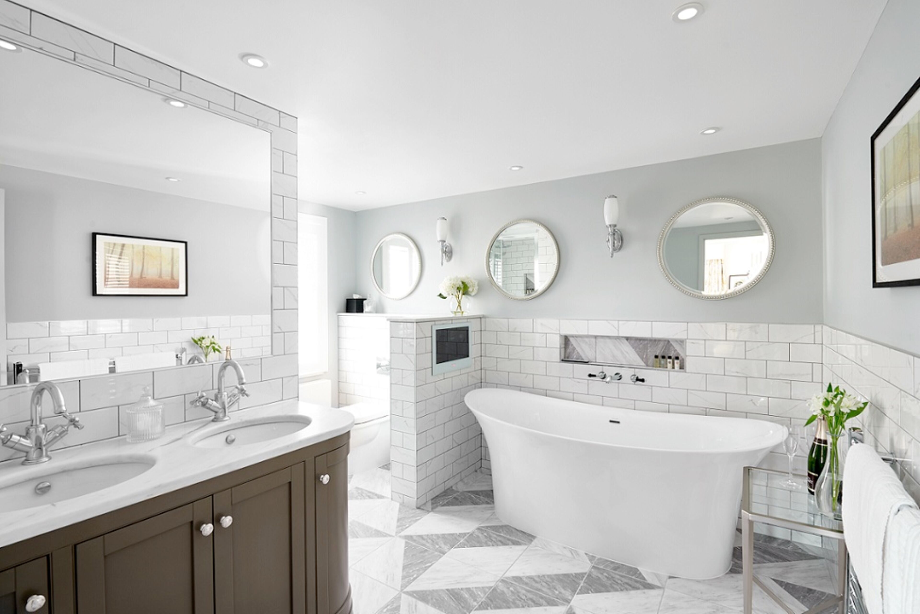 A modern bathroom with a freestanding bathtub, dual sinks, and a large mirror.
