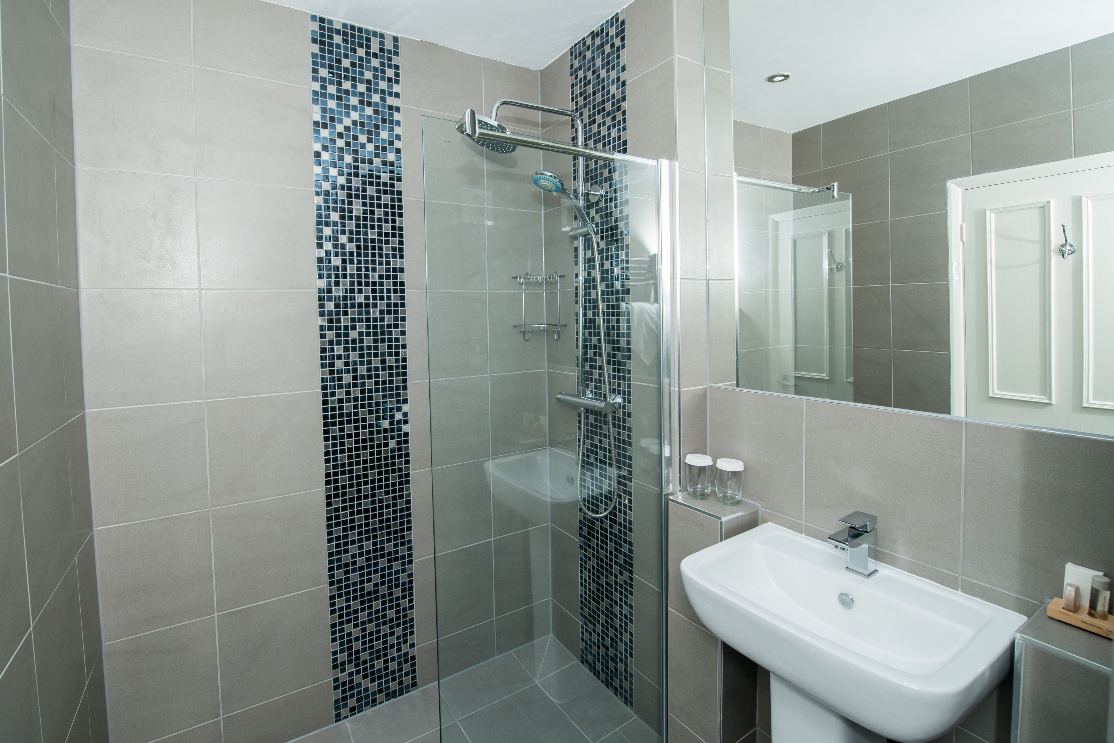A modern bathroom with a glass-enclosed shower, a white sink, and a tiled backsplash.