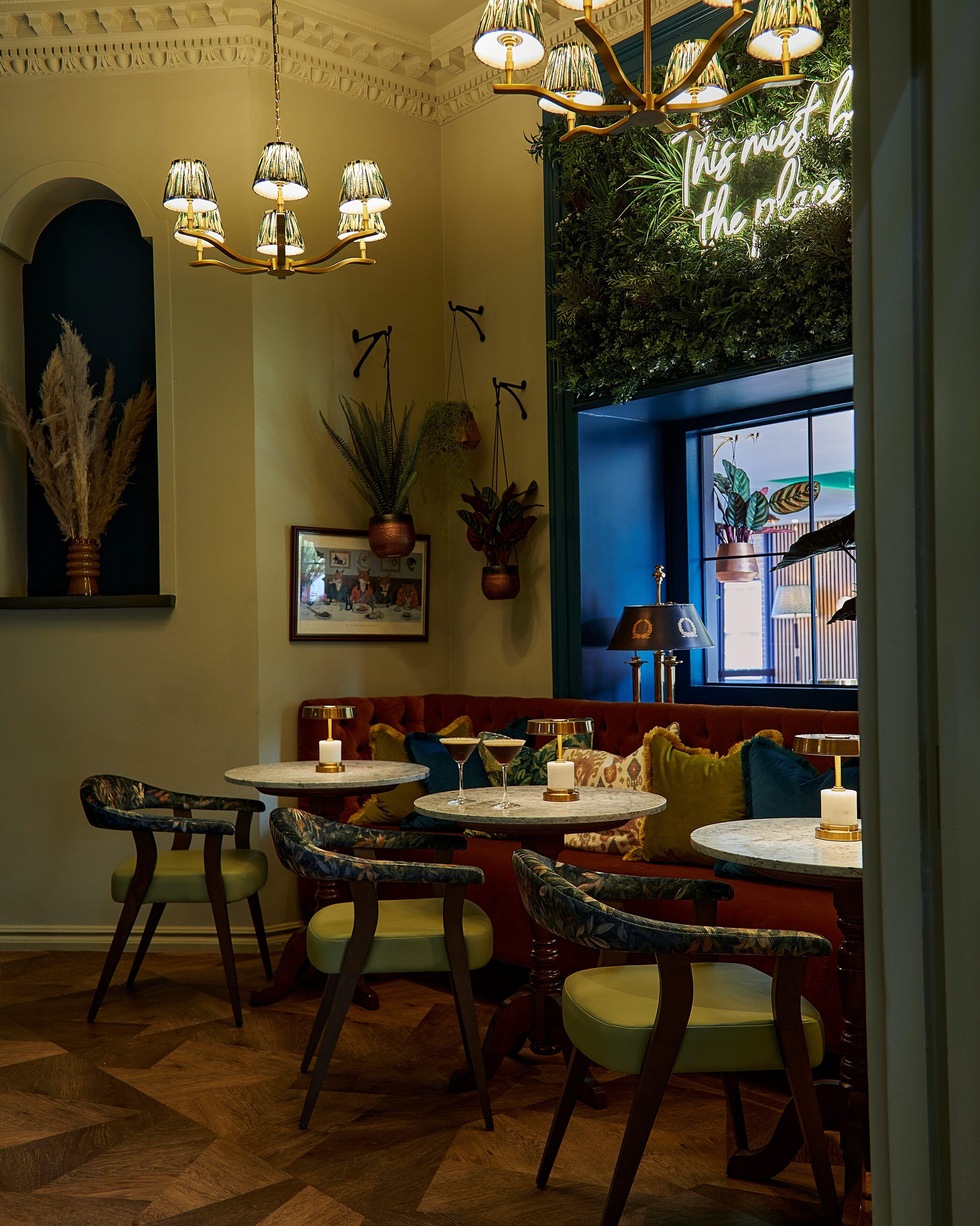 A restaurant interior with a cozy seating area, hanging lamps, and a neon sign.