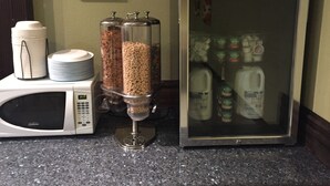En køkkenbordplade med en mikrobølgeovn, et Haier køleskab og en kaffemaskine.